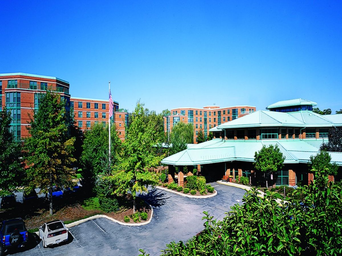 A view of a modern building complex surrounded by trees under a clear blue sky.