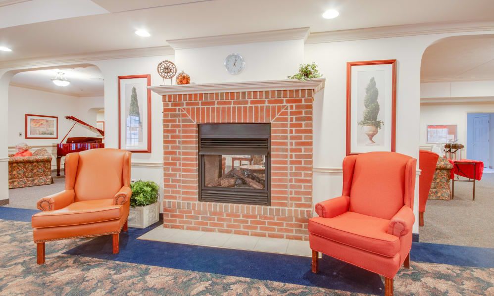 A cozy living room with a brick fireplace and orange armchairs.