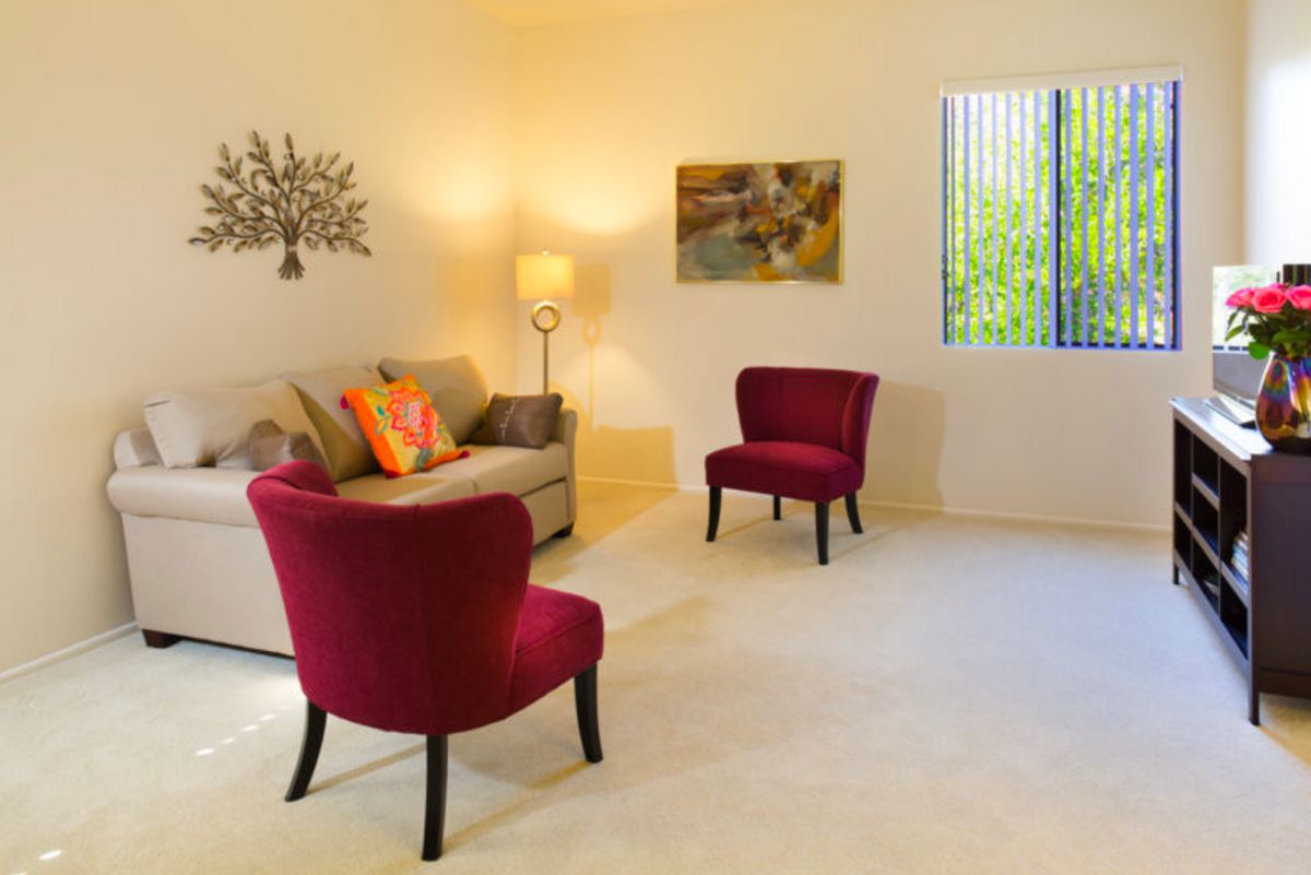 Bright and cozy living room with red chairs and a neutral sofa.
