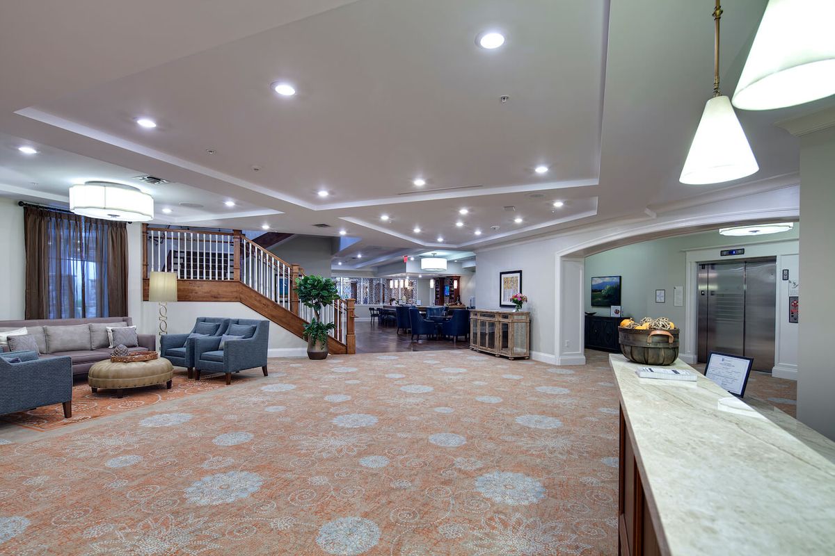 A spacious lobby area featuring comfortable seating, a staircase, and a patterned carpet.