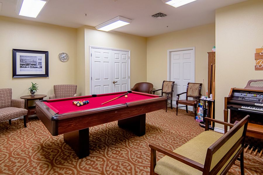 A cozy recreation room featuring a pool table with a red felt top, surrounded by comfortable seating.