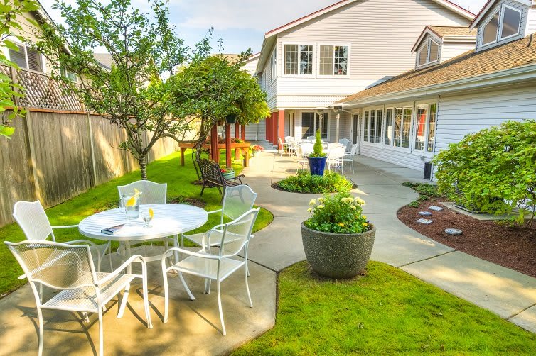 A sunny backyard patio with outdoor furniture and a well-maintained garden.