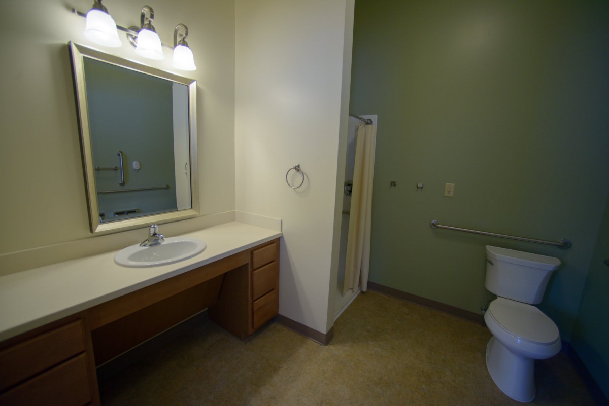 A modern bathroom with a sink, vanity, mirror, and shower area.