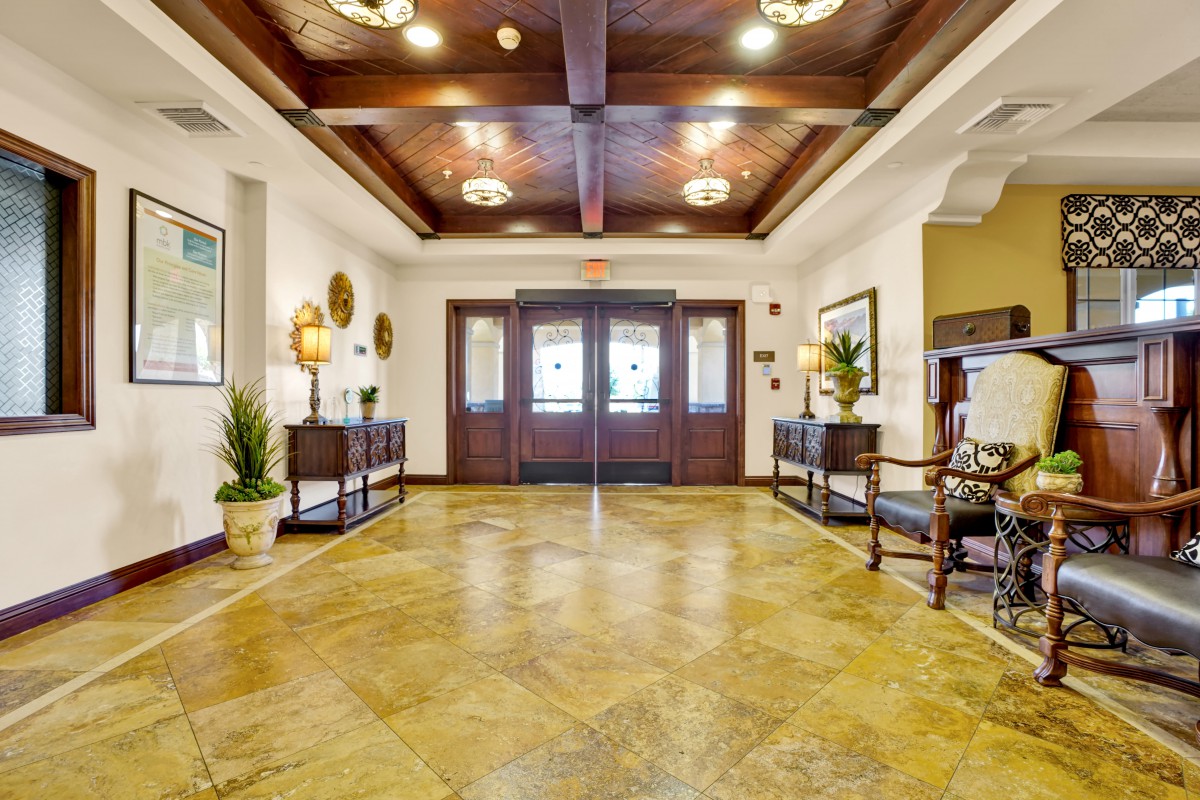 A spacious and elegantly decorated lobby area with a wooden ceiling and floor, featuring stylish furniture and potted plants.