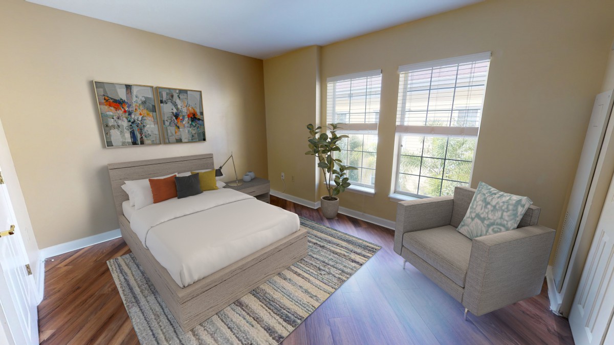 A cozy bedroom with a bed, chair, and large windows.