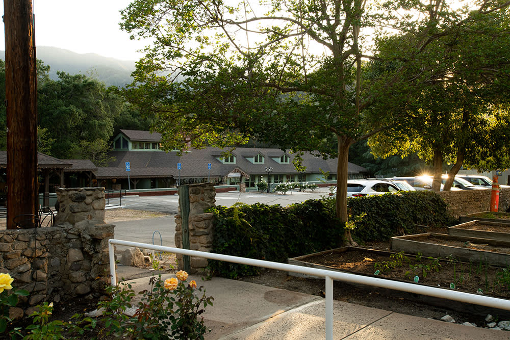 A scenic view of a building with a parking lot, surrounded by trees.