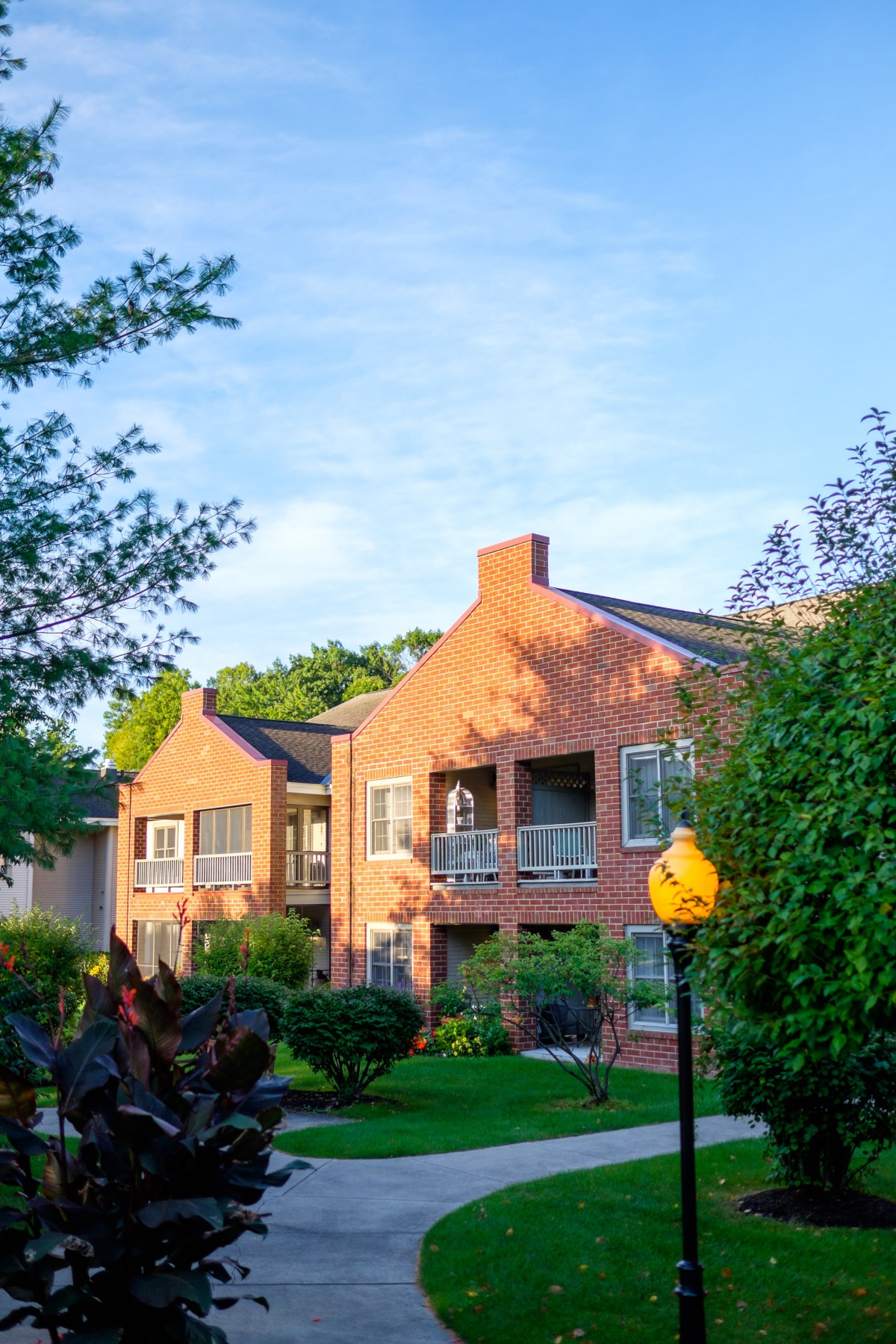 A residential apartment building surrounded by lush greenery on a sunny day.