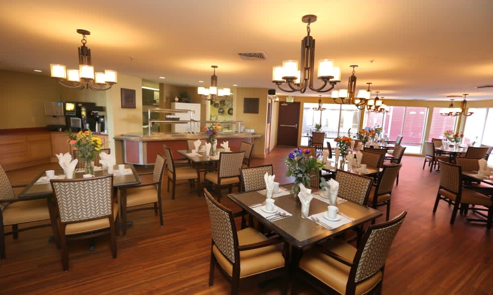 A beautifully arranged dining room with elegant tables and chairs, warm lighting, and tasteful decor.