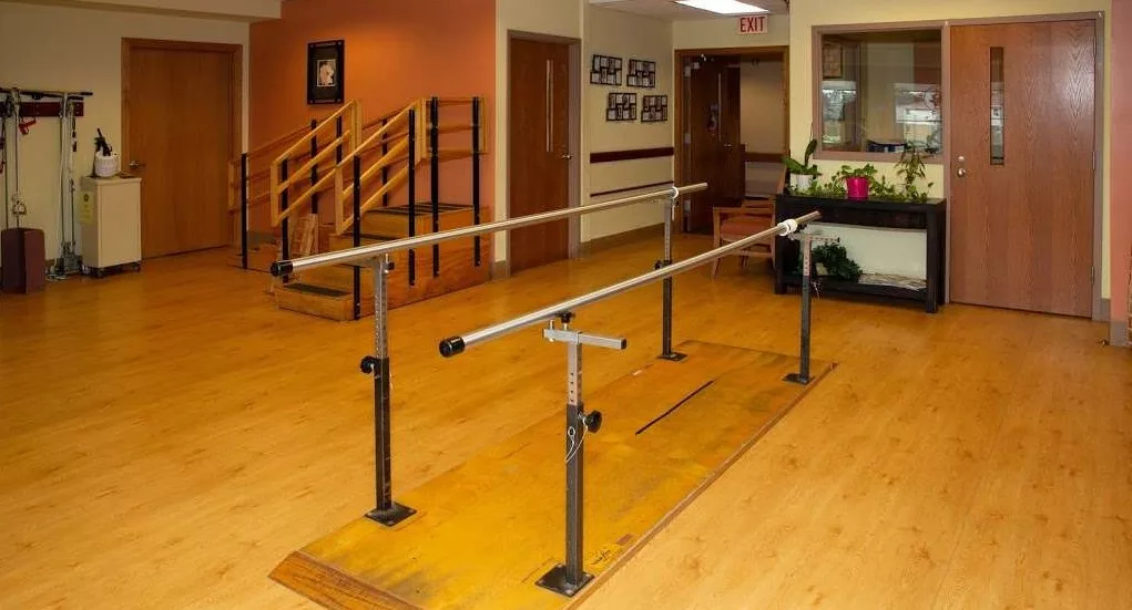 A physical therapy clinic featuring parallel bars used for rehabilitation exercises.