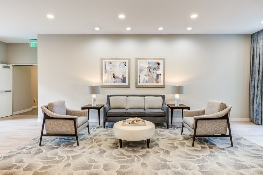 A modern living room setup featuring a sofa, armchairs, and a central coffee table, decorated in neutral tones.