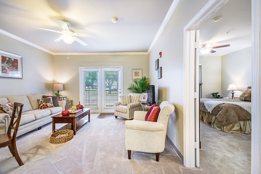 A bright and cozy living room featuring comfortable seating, a coffee table, and large windows providing natural light.