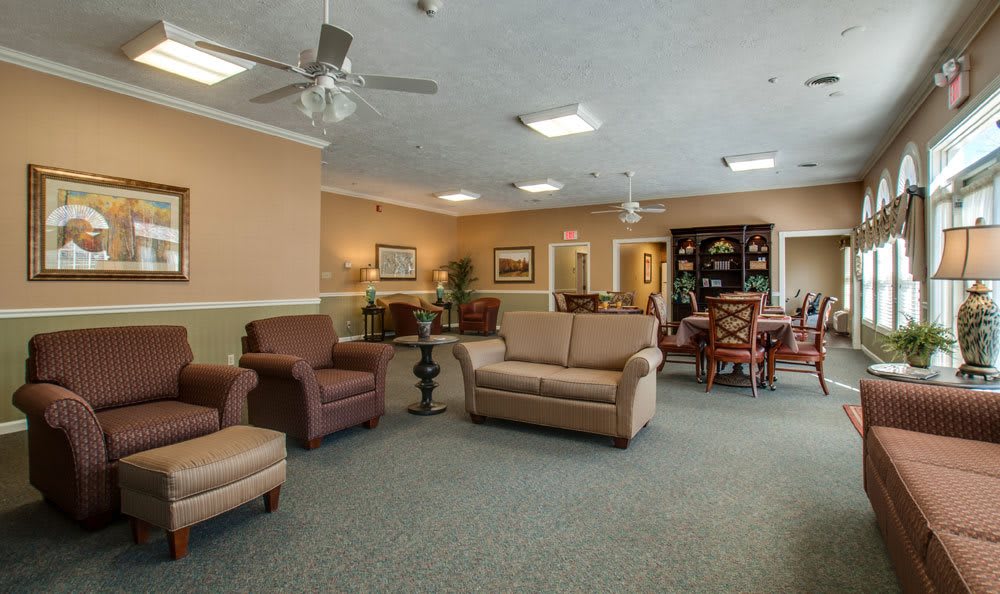 A spacious living room with comfortable seating, featuring sofas and chairs, decorated in warm tones.