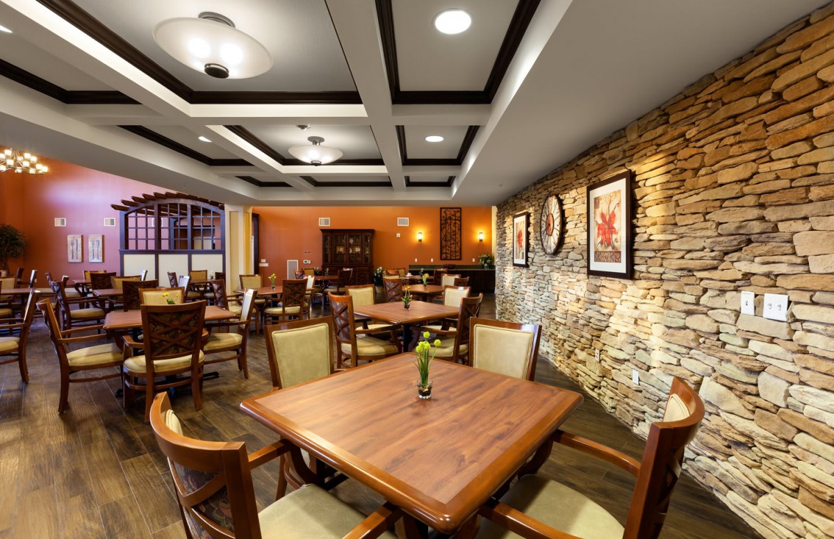 A cozy restaurant interior with neatly arranged tables and chairs, complemented by warm lighting and stylish wall decor.