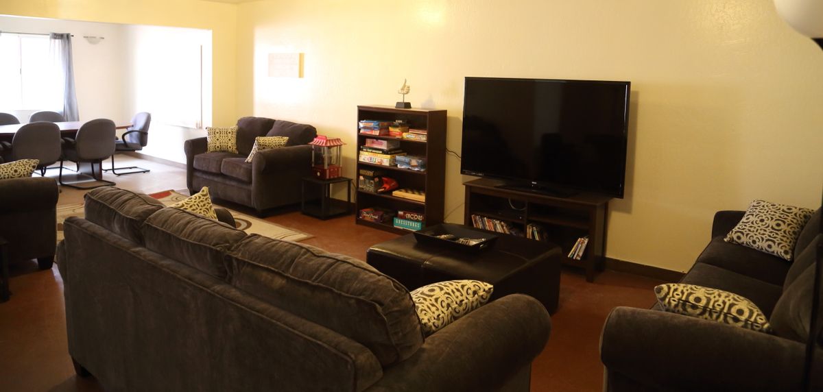 A cozy living room featuring a sofa set, a television, and a bookshelf filled with books.