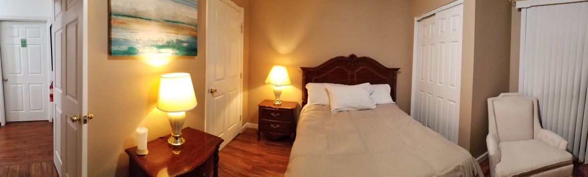 A cozy bedroom with a lamp on a nightstand beside the bed.