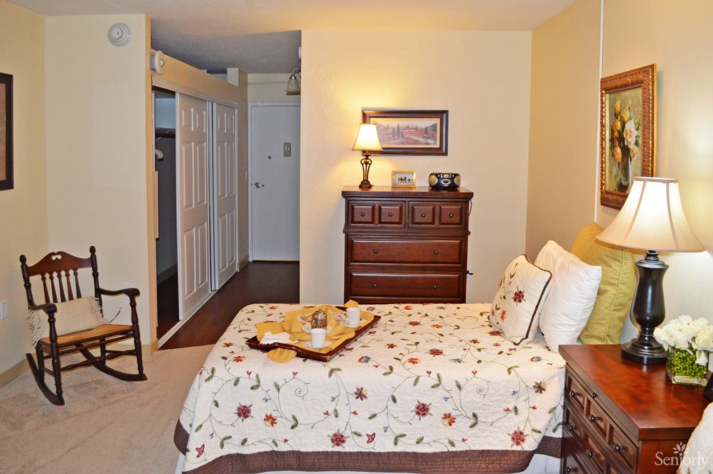 A cozy bedroom with a neatly made bed, a dresser, and a lamp.