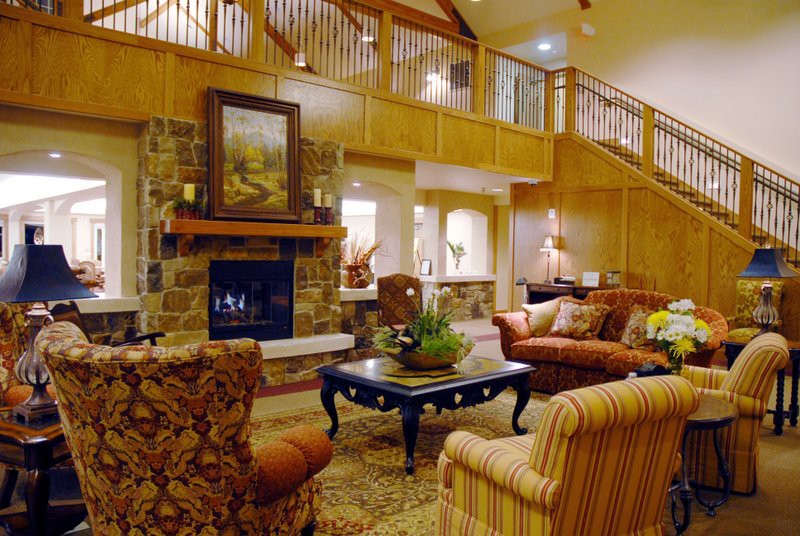 A cozy living room with a traditional design featuring a stone fireplace and comfortable seating.