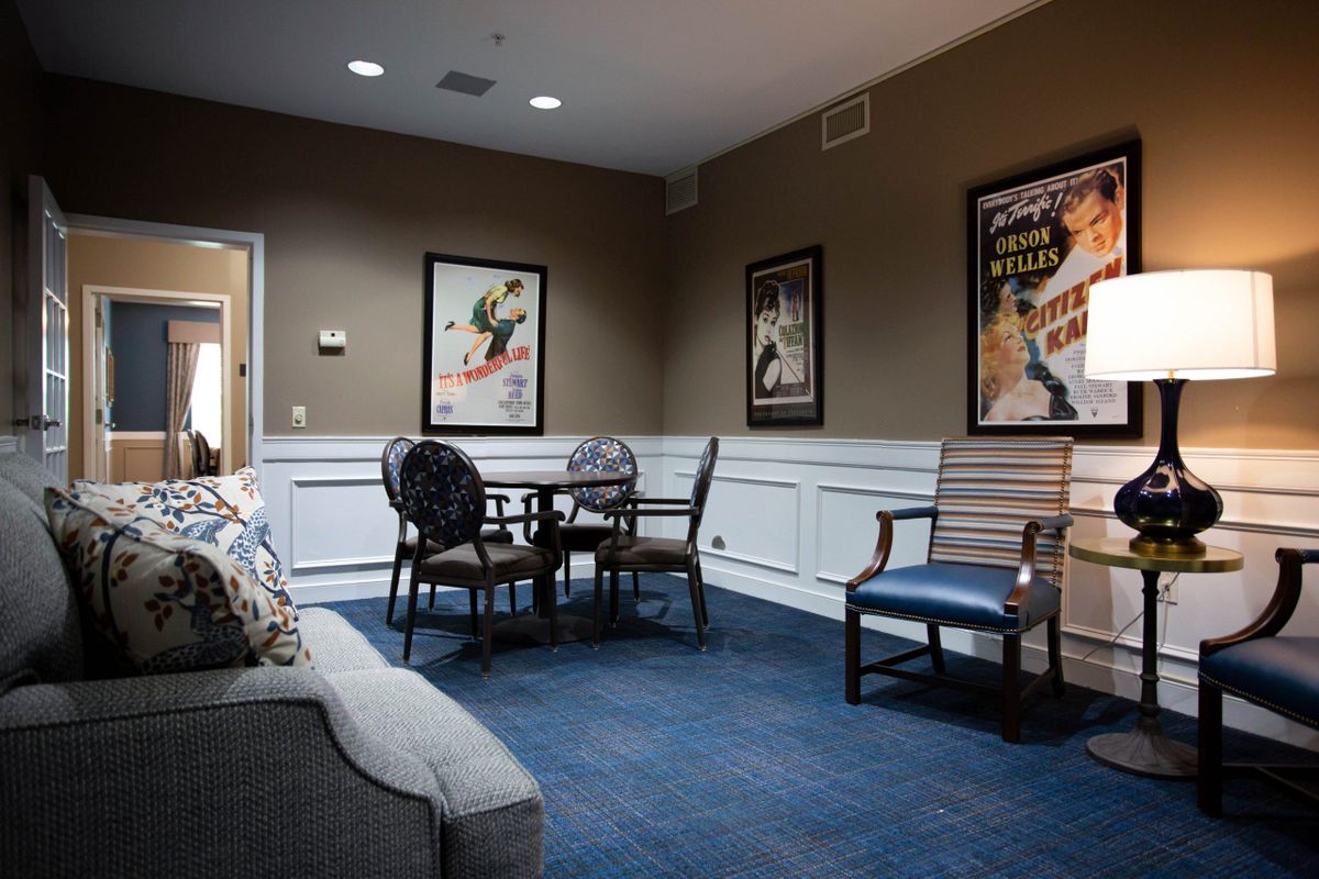 A cozy room featuring a small table with chairs, a sofa, and movie posters on the walls.