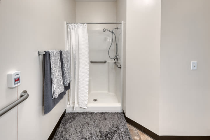 A modern bathroom with a minimalist shower setup, complete with a curtain and towels.