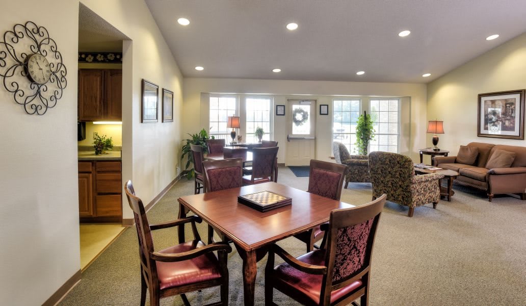 A well-lit interior space featuring a wooden dining table with chairs, surrounded by large windows and tasteful decor.