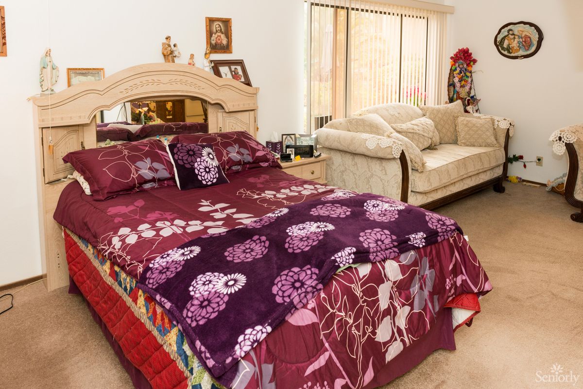 A cozy bedroom with a colorful floral bedspread and a comfortable couch in the corner.