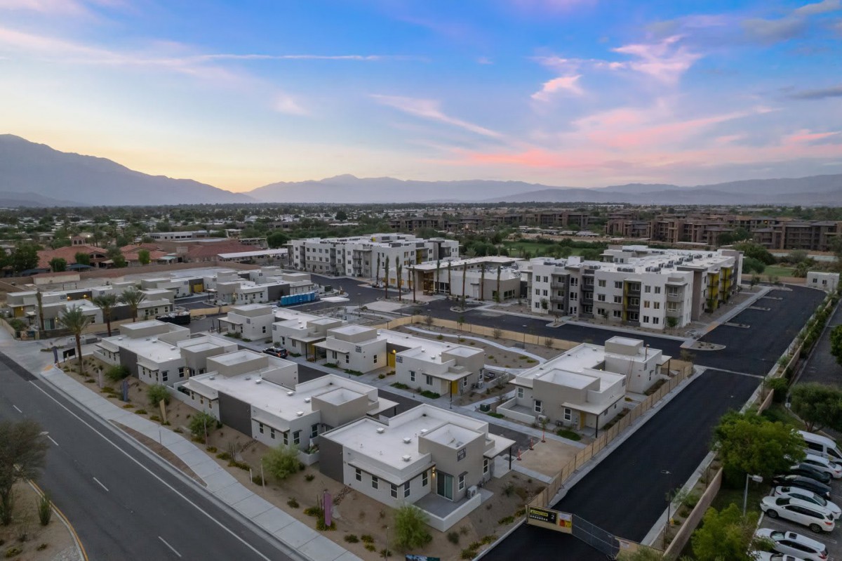Aerial view of a suburban residential area with modern architecture and mountains in the background during sunset.