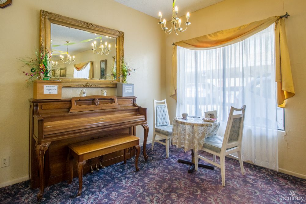 A cozy living room with a piano, elegant furniture, and a chandelier.