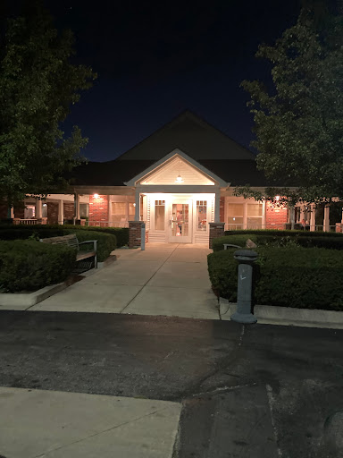A well-lit building surrounded by landscaped greenery at night.