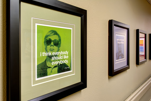 A framed art piece featuring a green-toned portrait with the quote 'I think everybody should like everybody.'