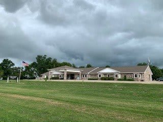 A large building with a wide lawn under a cloudy sky.
