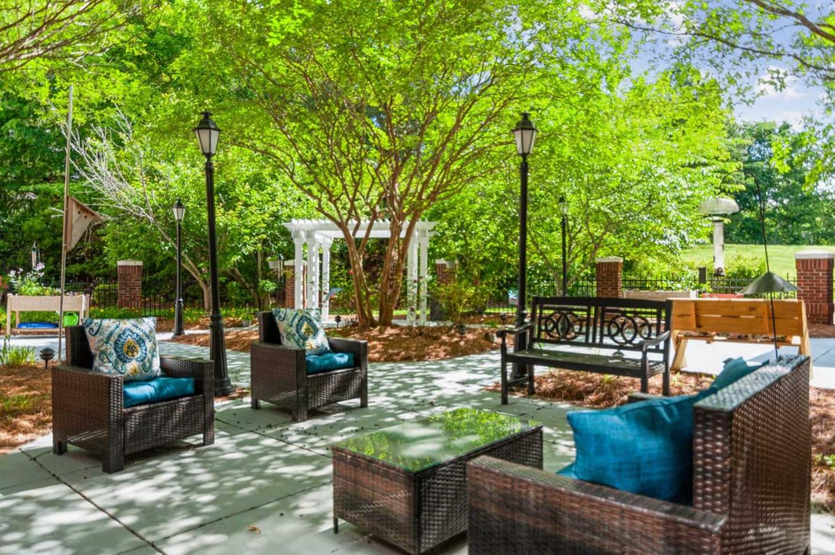 A tranquil outdoor patio surrounded by lush greenery, featuring comfortable seating and elegant design.
