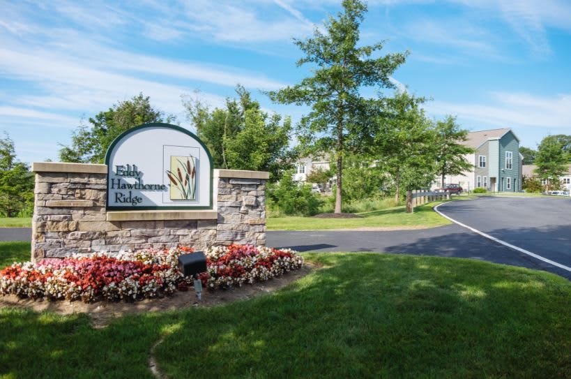Entrance sign to a residential complex surrounded by greenery and flowers.