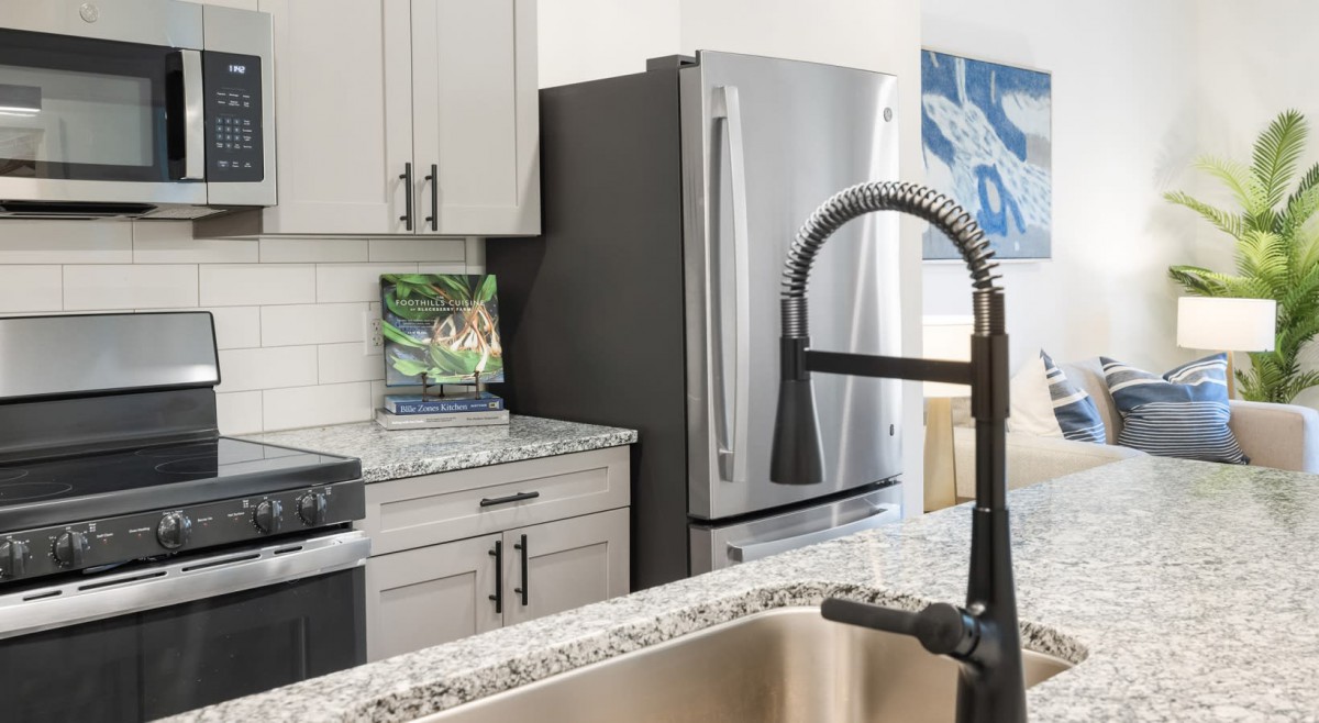 A modern kitchen with a stainless steel refrigerator, granite countertops, and a stylish faucet.