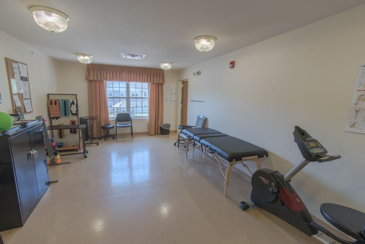 A rehabilitation room equipped with exercise equipment and therapy beds.