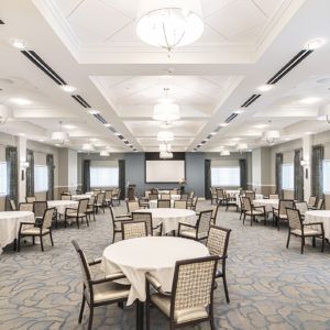 An empty banquet hall with round dining tables and elegant chandeliers, ready for an event.