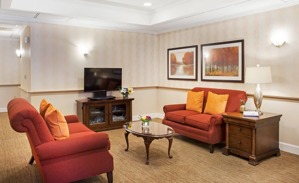 A cozy living room with red sofas, a wooden coffee table, and a television.