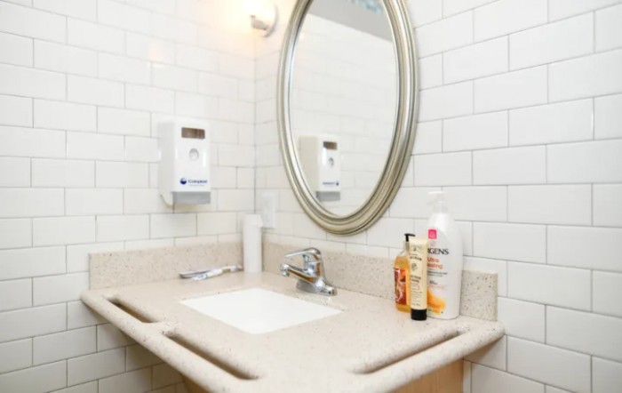 A clean bathroom sink with a mirror and various toiletries on the counter.