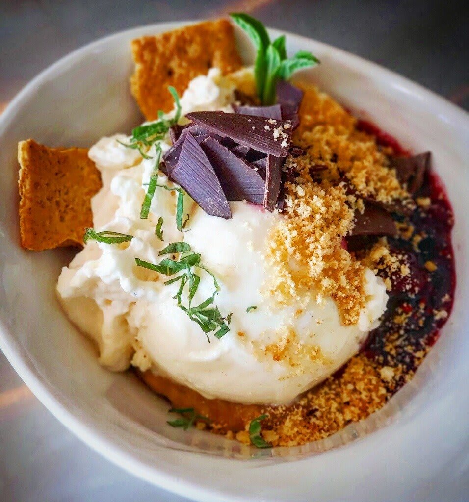 A delicious dessert topped with ice cream, chocolate shavings, and garnished with fresh herbs.