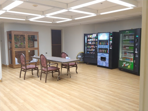 A spacious room featuring a table and chairs, complemented by vending machines for refreshments.
