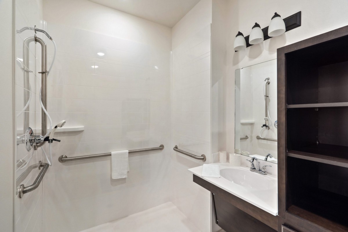 A modern, minimalist bathroom featuring a walk-in shower and a sleek sink with a mirror.