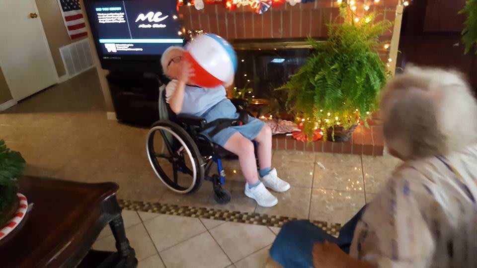 A person in a wheelchair playing with a beach ball indoors, surrounded by holiday decorations.