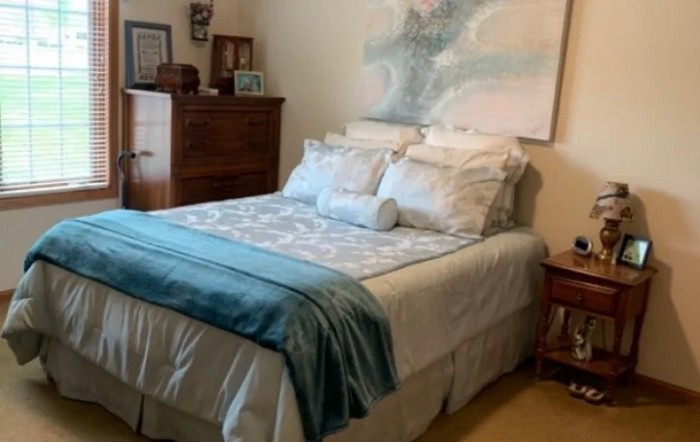 A cozy bedroom with a neatly made bed and wooden furniture.