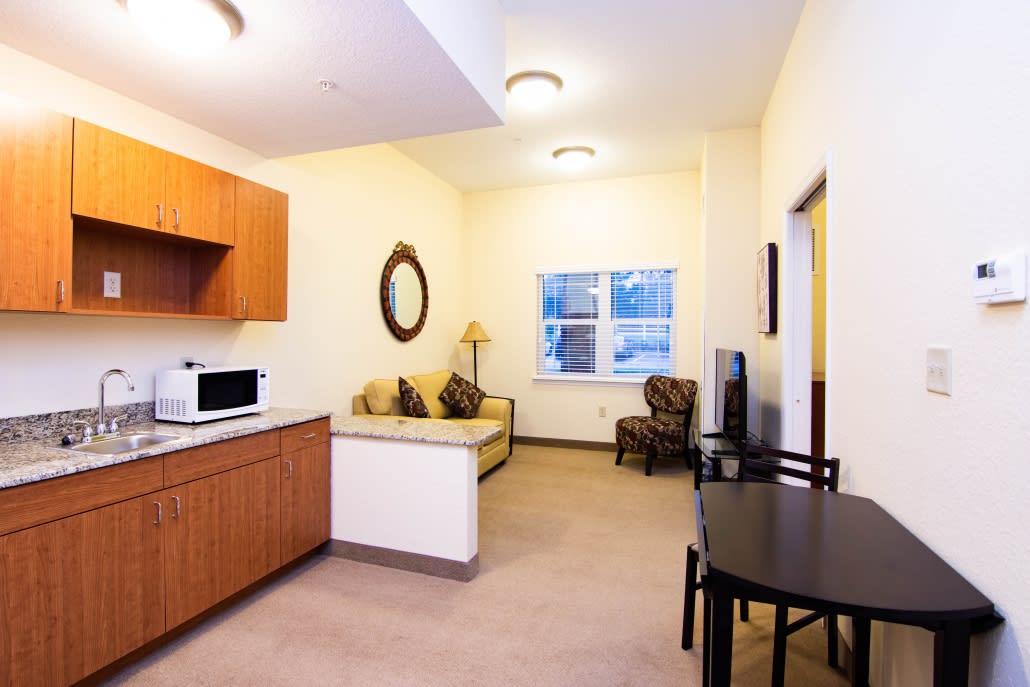 A cozy apartment living area featuring a kitchenette, sofa, and dining table.