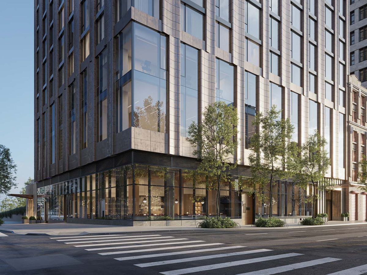 A modern urban building with large windows at a street corner, surrounded by trees.