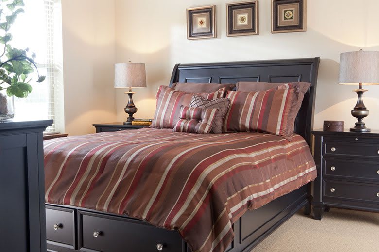 A cozy bedroom with a neatly made bed featuring striped bedding and a stylish headboard.