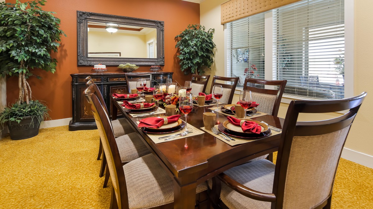 A beautifully set dining table with elegant dinnerware and red napkins, creating a warm and inviting atmosphere.