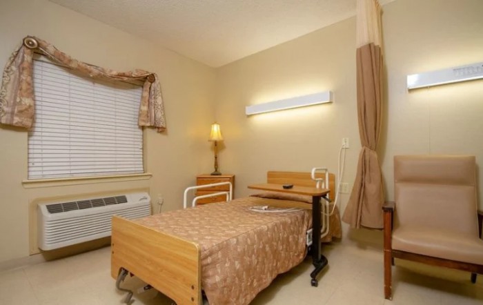 A hospital room with a bed, medical equipment, and a window with curtains.