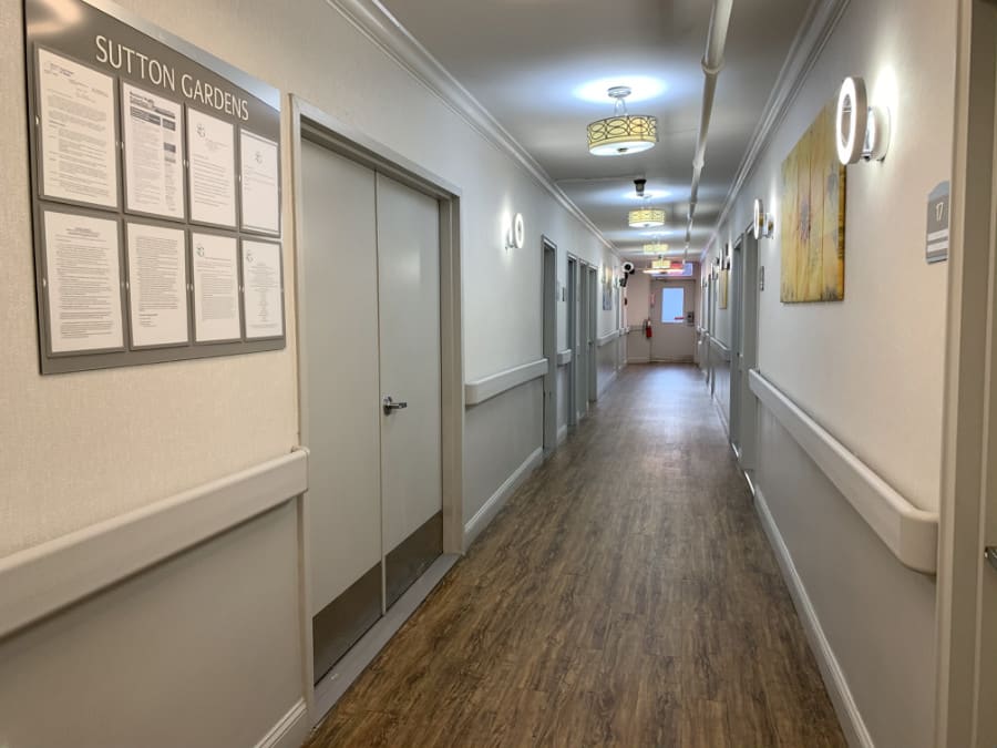 A long, well-lit hallway with multiple doors, typically found in an institutional setting.