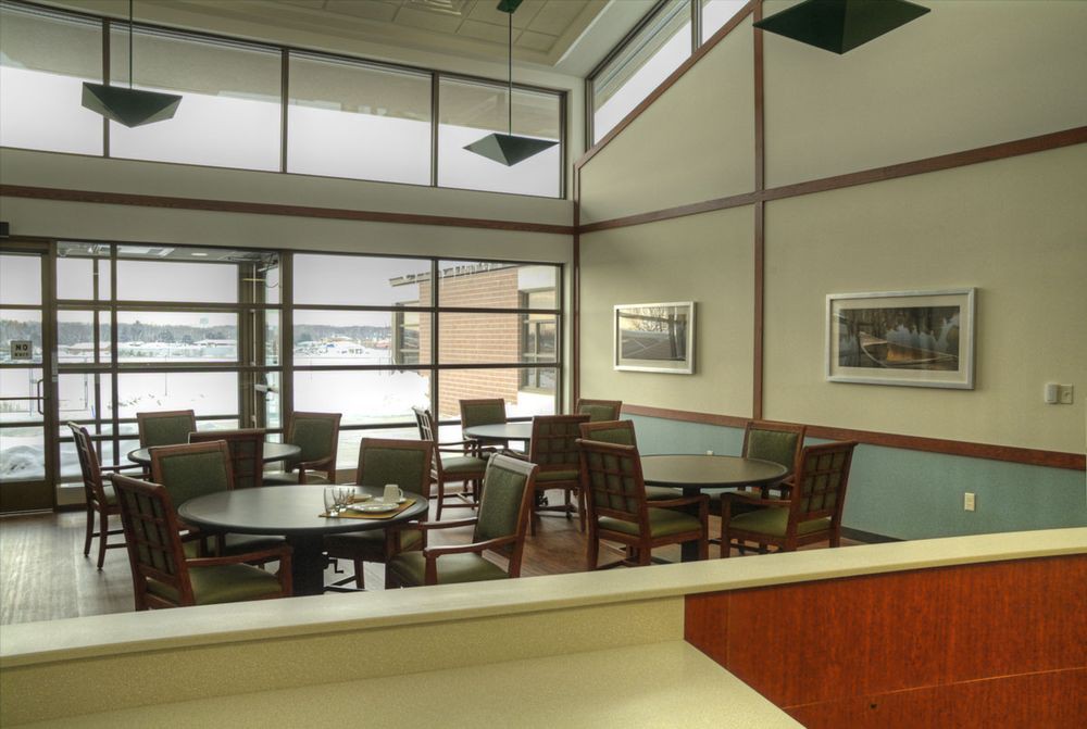 A modern dining area with wooden furniture and large windows providing natural light.