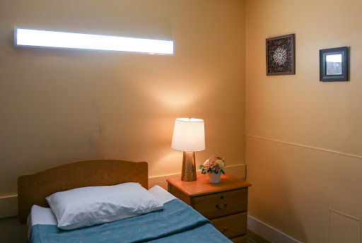 A cozy bedroom featuring a neatly made bed, a bedside lamp, and decorative elements on the wall.